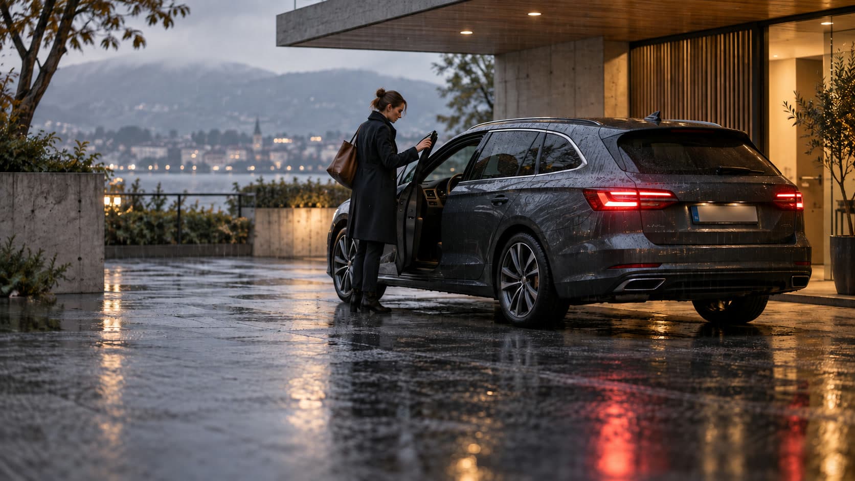 Femme refermant la portière d’une voiture sous une pluie fine devant une maison contemporaine